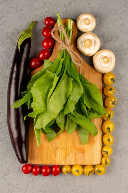 Vue de dessus tomates feuilles champignons avec aubergine noire sur le sol gris