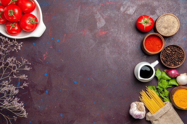 Vue de dessus des tomates fraîches avec assaisonnements sur fond noir