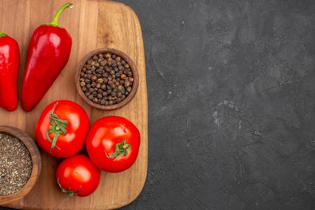 Vue de dessus des tomates fraîches avec assaisonnements et poivre sur fond noir