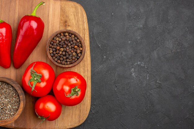 Vue de dessus des tomates fraîches avec assaisonnements et poivre sur fond noir