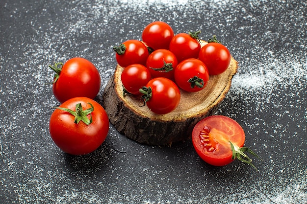 Vue de dessus des tomates fraîches avec des tiges sur planche de bois et sur fond noir wite