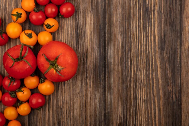 Vue de dessus des tomates orange et rouges arrondies isolées sur un mur en bois avec espace copie