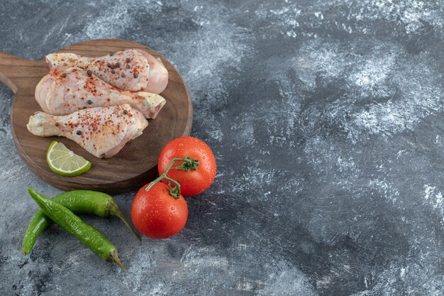 Vue de dessus. Tomates et poivrons biologiques frais avec cuisses de poulet crues