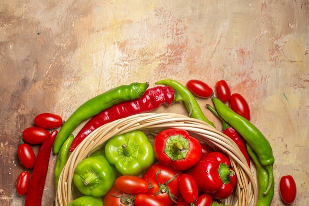 Photo gratuite vue de dessus tomates poivrons verts et rouges dans des légumes panier en osier sur fond ambre
