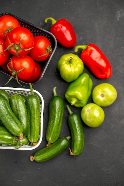 Vue de dessus des tomates rouges fraîches avec des concombres sur fond sombre