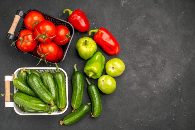 Vue de dessus des tomates rouges fraîches avec des concombres sur fond sombre