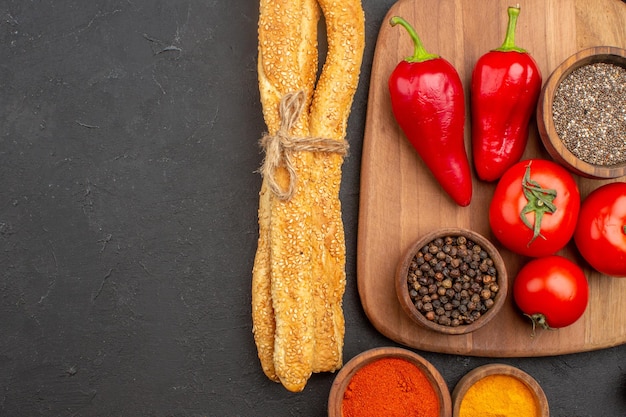 Vue de dessus des tomates rouges fraîches avec du pain et des assaisonnements sur fond noir