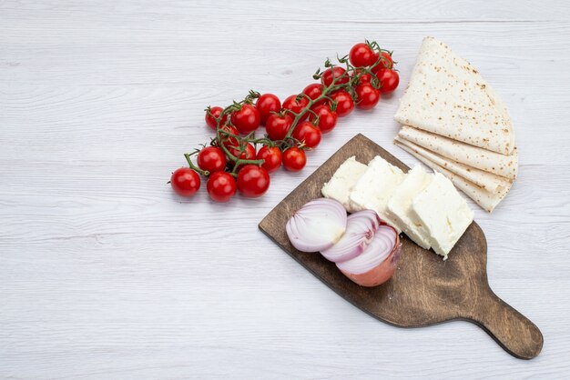 Vue de dessus tomates rouges fraîches avec des oignons de fromage blanc en tranches et lavash sur le fond blanc repas repas déjeuner photo légume