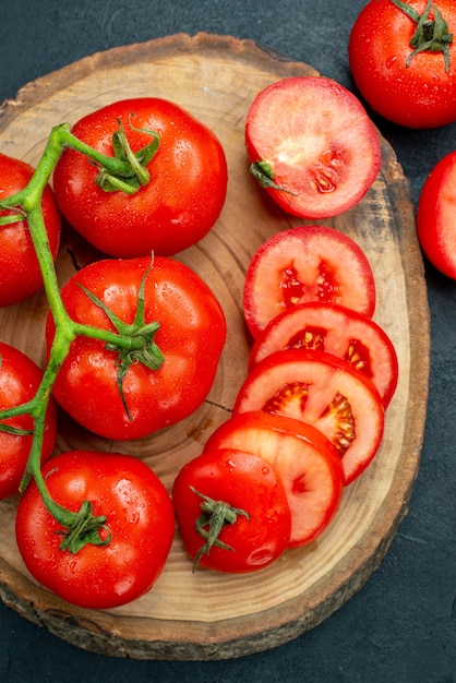 Photo gratuite vue de dessus des tomates rouges fraîches sur planche de bois sur fond sombre