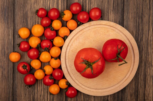 Vue de dessus des tomates rouges fraîches sur une planche de cuisine en bois avec des tomates cerises isolé sur un mur en bois