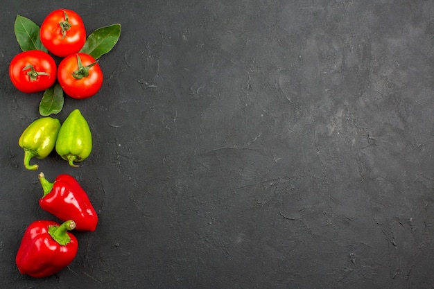 Vue de dessus tomates rouges fraîches avec des poivrons sur la table de couleur sombre salade mûre