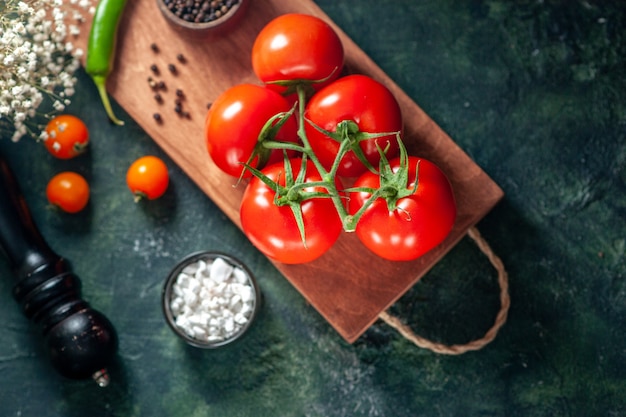 Vue de dessus tomates rouges fraîches sur une surface sombre légume repas frais couleur poivre salade mûre alimentaire