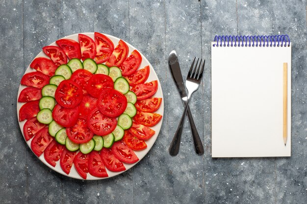 Vue de dessus tomates rouges fraîches en tranches de salade fraîche sur le bureau gris