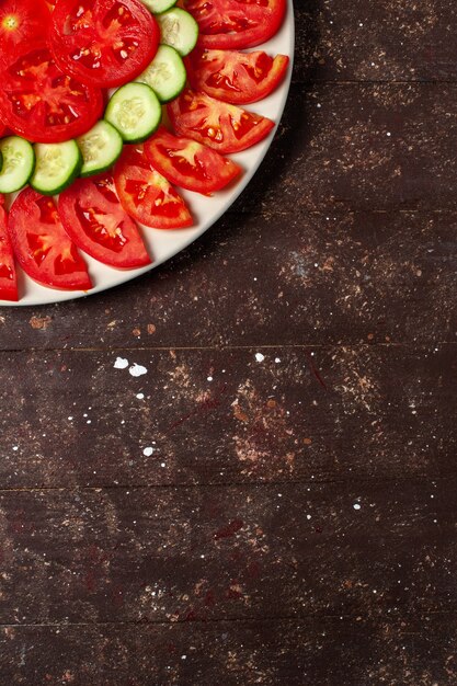 Vue de dessus tomates rouges fraîches en tranches de salade fraîche sur espace brun