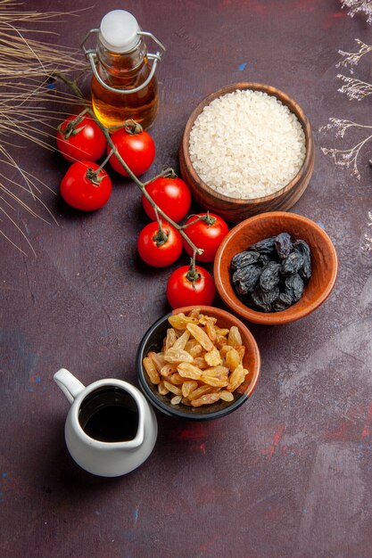 Vue de dessus tomates rouges avec des raisins secs sur une surface sombre salade de légumes raisins santé