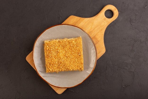 Une vue de dessus tranche de gâteau au miel délicieux et à l'intérieur de la plaque sur la table noire gâteau biscuit sucre sucré