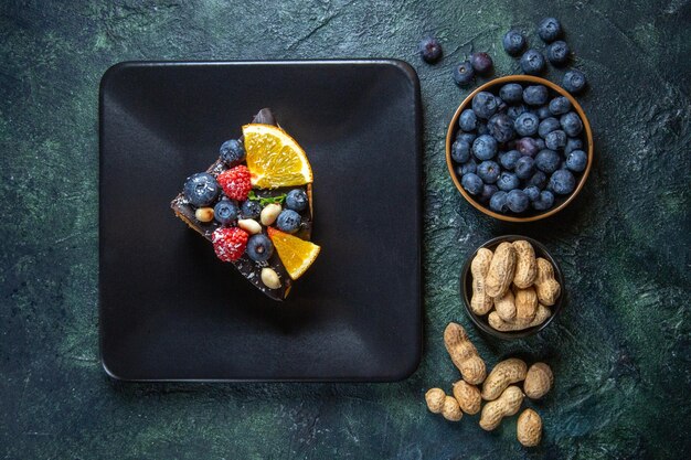 Vue de dessus de la tranche de gâteau délicieux gâteau au chocolat avec des fruits à l'intérieur de la plaque sur noir