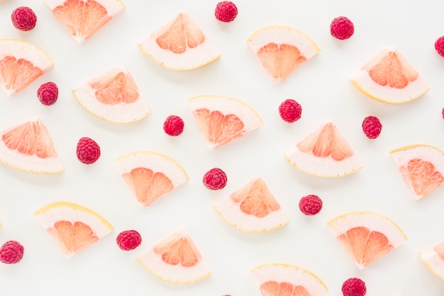 Une vue de dessus de la tranche de pamplemousse et de framboises sur fond blanc