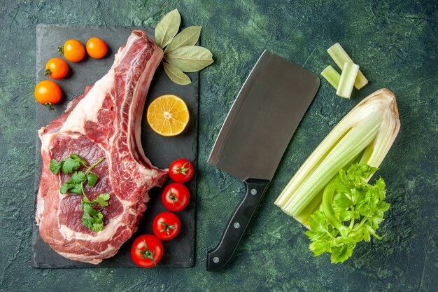 Vue de dessus tranche de viande fraîche avec des tomates sur fond bleu foncé nourriture viande animal boucher poulet couleur vache