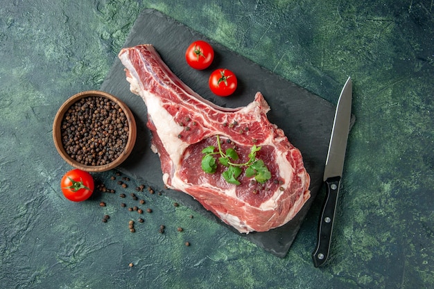 Photo gratuite vue de dessus tranche de viande fraîche avec tomates et poivre sur fond bleu foncé cuisine animal vache poulet nourriture couleur viande de boucher