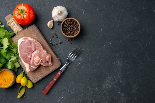 Vue de dessus tranche de viande fraîche viande crue avec des légumes verts sur un plat de barbecue sombre poivre cuisine nourriture vache salade repas animal nourriture