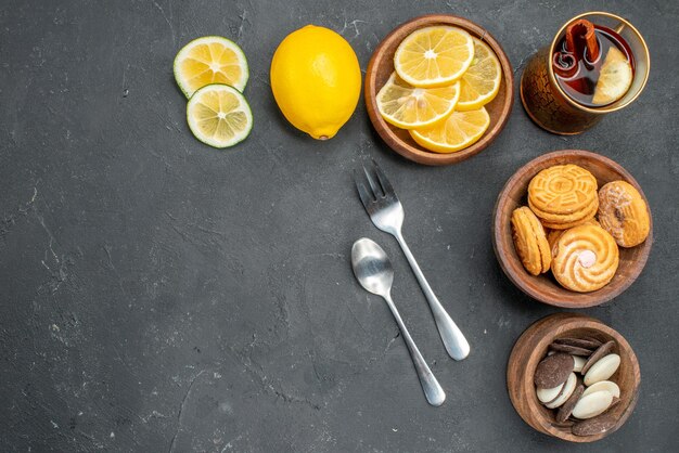 Vue de dessus des tranches de citron frais avec des cookies sur une surface sombre