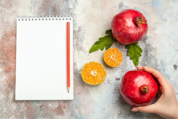 Vue de dessus tranches de citron grenades rouges crayon rouge sur ordinateur portable sur surface nue