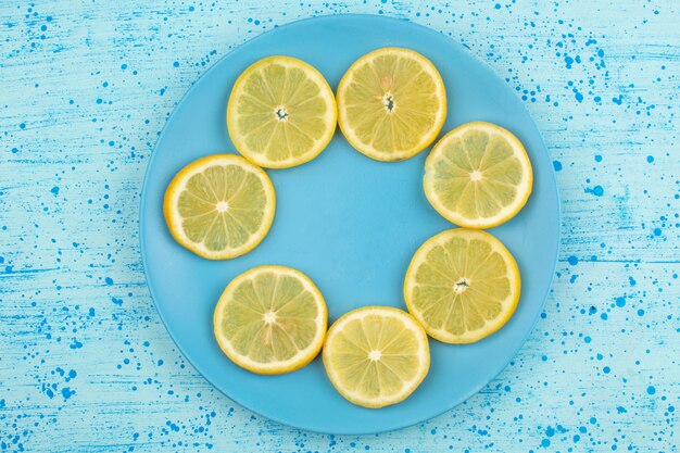 Vue de dessus en tranches de citron juteux aigre-doux à l'intérieur de la plaque bleue sur le plancher bleu vif