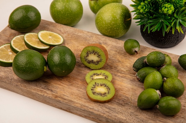 Vue de dessus de tranches fraîches de limes sur une planche de cuisine en bois avec kiwi feijoa et pommes vertes isolé sur fond blanc