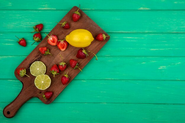 Vue de dessus des tranches de fraise sur une planche de cuisine en bois sur un fond en bois vert avec espace copie