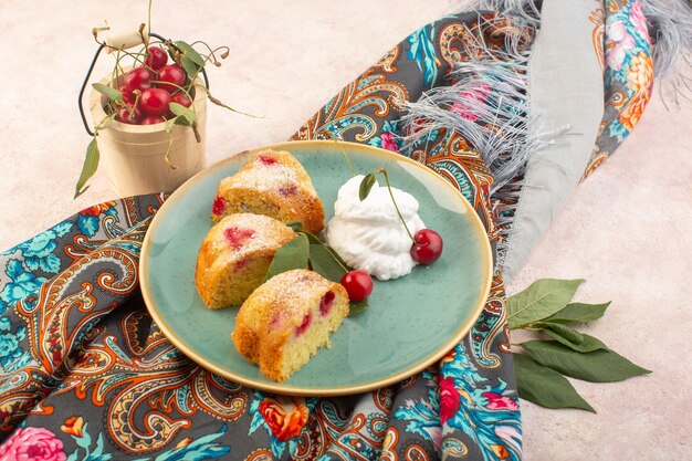 Une vue de dessus des tranches de gâteau aux cerises avec de la crème et des fruits frais sur le bureau rose gâteau biscuit sucré