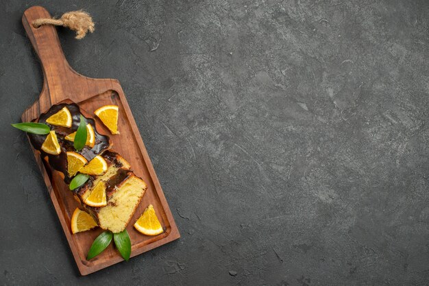 Vue de dessus de tranches de gâteau moelleux fraîchement cuit sur une planche à découper en bois sur une table sombre