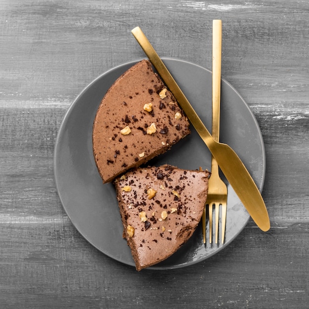 Vue de dessus des tranches de gâteau sur une plaque avec des couverts dorés