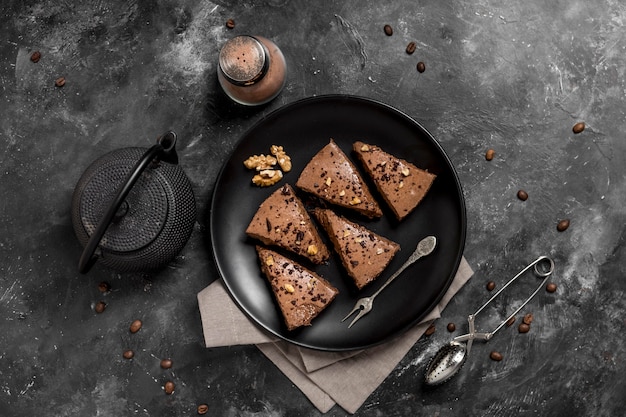 Vue de dessus des tranches de gâteau sur une plaque avec une théière et des grains de café