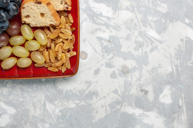 Vue de dessus des tranches de gâteau avec des raisins et des raisins secs à l'intérieur de la plaque rouge sur une surface blanche claire