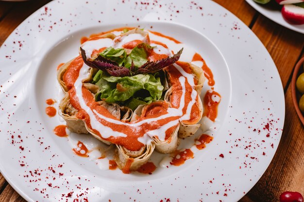 Vue de dessus des tranches de kebab lula enveloppées dans du pain plat garni de sauce tomate