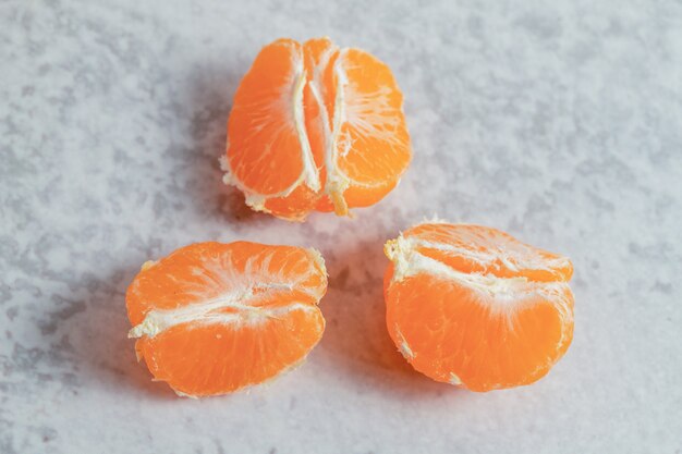 Vue de dessus des tranches de mandarine fraîches sur une surface grise.