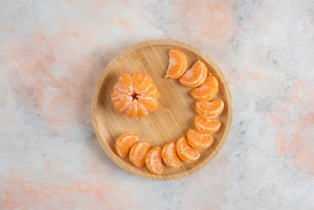 Vue de dessus des tranches de mandarines clémentine pelées sur plaque en bois