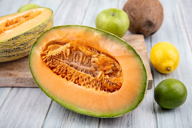 Vue de dessus des tranches de melon cantaloup frais sur planche de cuisine en bois avec des citrons sur bois gris