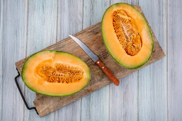 Vue de dessus des tranches de melon cantaloup frais sur planche de cuisine en bois avec couteau sur bois gris