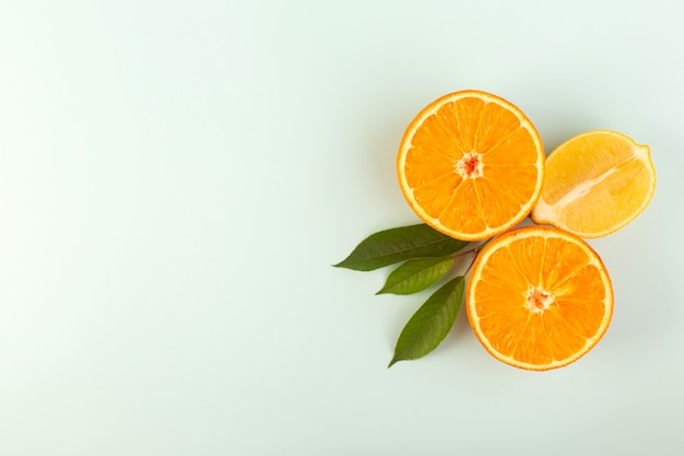 Une vue de dessus en tranches orange frais mûrs juteux moelleux isolés la moitié des morceaux coupés avec des feuilles vertes sur le fond blanc couleur fruits agrumes