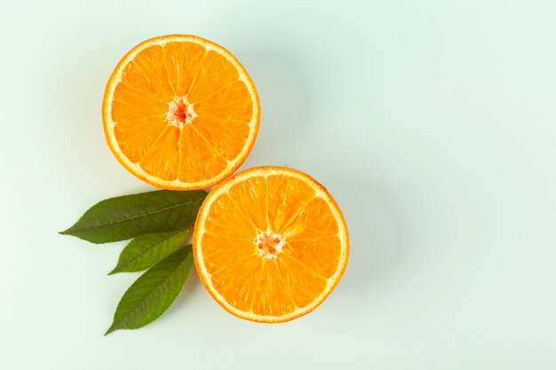 Une vue de dessus en tranches orange frais mûrs juteux moelleux isolés la moitié des morceaux coupés avec des feuilles vertes sur le fond blanc couleur fruits agrumes