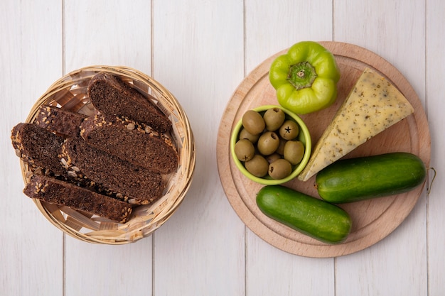 Vue De Dessus Des Tranches De Pain Noir Avec Du Fromage Et Des Concombres Aux Poivrons Sur Un Support Avec Des Olives Sur Fond Blanc