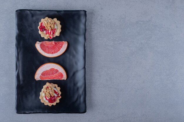 Vue de dessus des tranches de pamplemousse frais avec cookie sur plaque noire