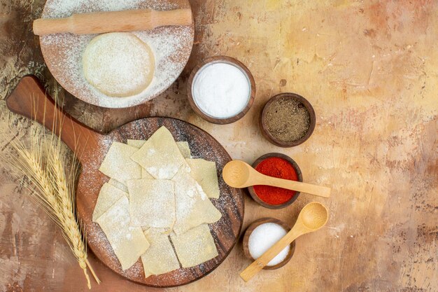 Vue de dessus des tranches de pâte crue avec de la farine sur le bureau de la crème