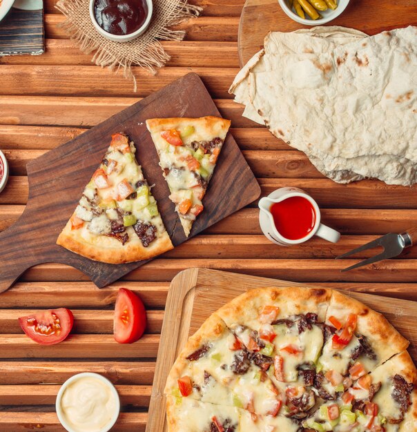 Vue de dessus des tranches de pizza à la viande sur une planche à découper en bois