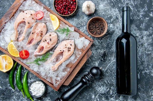 Vue de dessus des tranches de poisson cru avec des tranches de citron glacé sur une bouteille de vin en bois sur la table