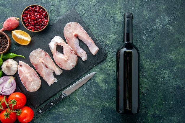 Vue de dessus des tranches de poisson frais avec des tomates rouges sur fond bleu foncé océan viande fruits de mer poivron plat nourriture repas de mer eau vin