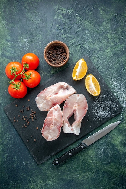 Photo gratuite vue de dessus des tranches de poisson frais avec des tomates rouges sur une table bleu foncé océan viande fruits de mer repas de mer nourriture poivre plat