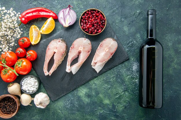 Vue de dessus des tranches de poisson frais avec des tomates rouges sur table sombre fruits de mer océan viande plat de repas de mer salade alimentaire eau poivre vin